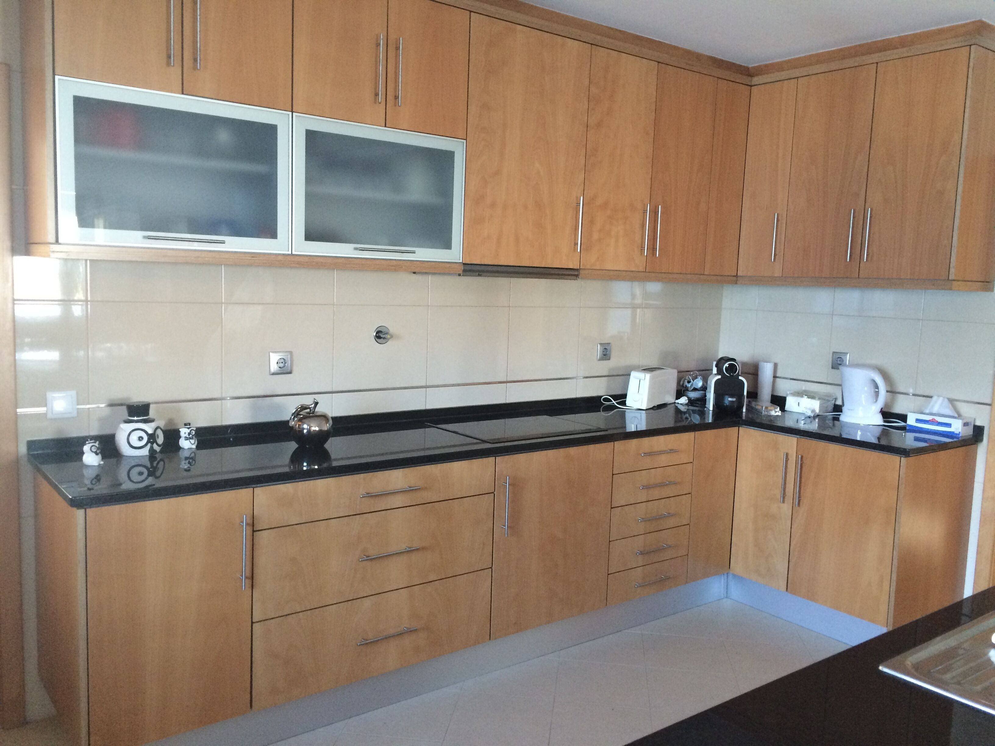 A kitchen with wooden cabinets, a black countertop, and a microwave above it.