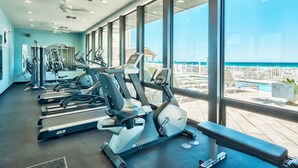 Ein Fitnessraum mit unterschiedlichen Trainingsgeräten und Blick auf den Strand.