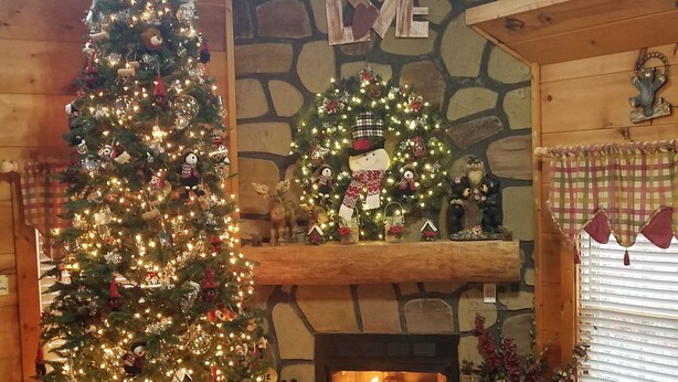 Ein gemütliches Wohnzimmer mit einem großen Weihnachtsbaum, einem Kamin und einer Steinwand.