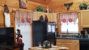 Ein gemütliches Blockhaus-Interieur mit einem Holzesstisch, Küchenzeile und einem Fernseher.