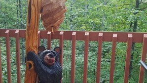 Eine Holzskulptur eines Bären, der auf einem Balkongeländer einen Baum erklimmt.