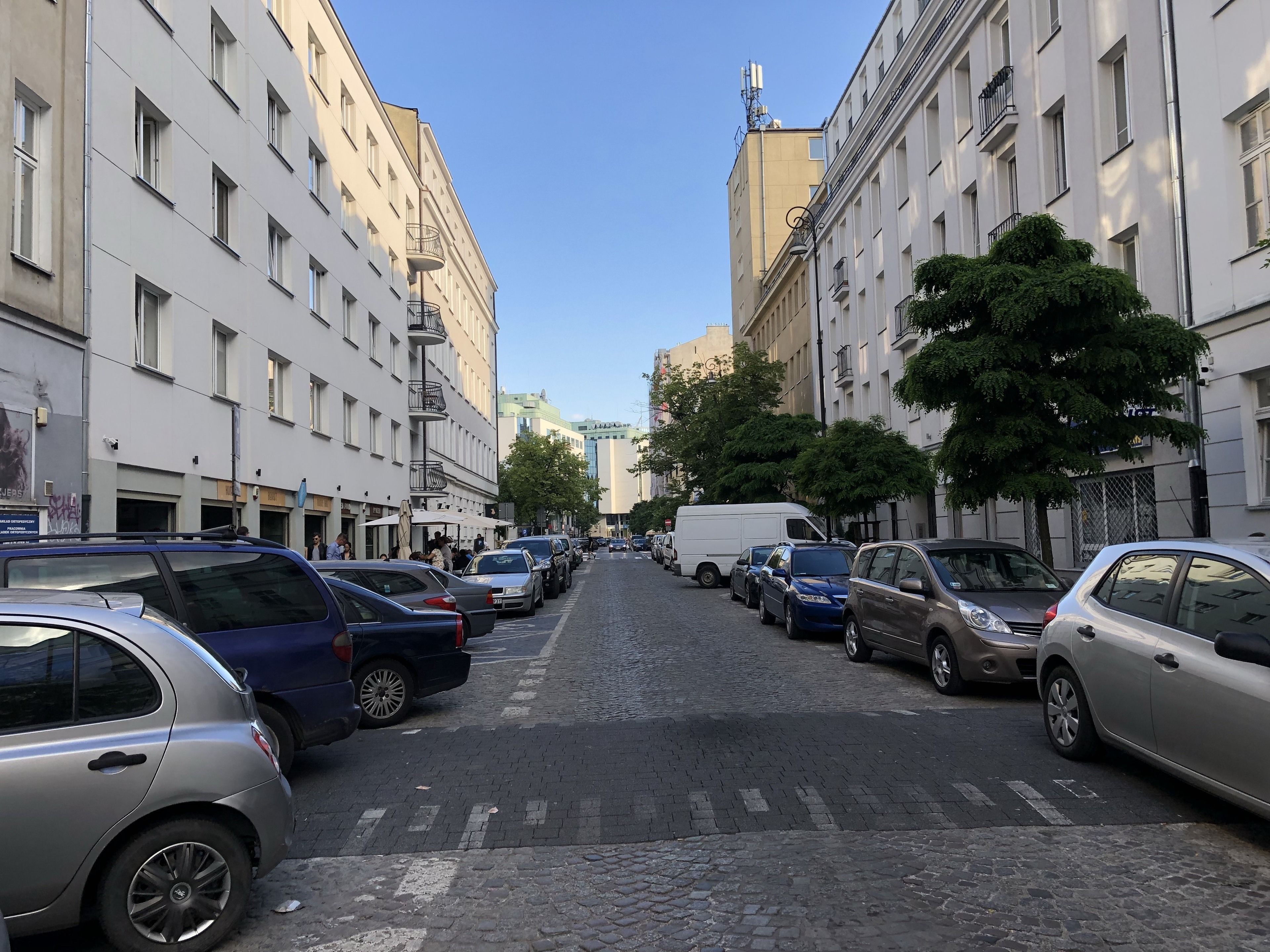 Une rue bordée de voitures garées et d’immeubles.