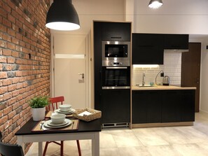 Una cocina compacta con pared de ladrillo, electrodomésticos modernos y un comedor con una mesa dispuesta para dos.