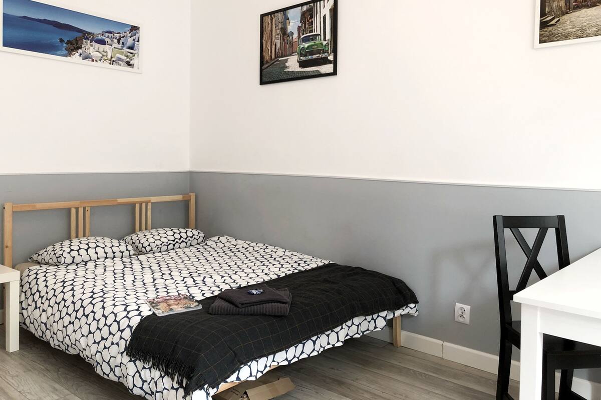 Ein Schlafzimmer mit einem Bett, einem Schreibtisch und zwei gerahmten Bildern an der Wand.