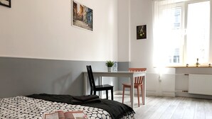 Een slaapkamer met een bed, een bureau, een stoel en een raam.