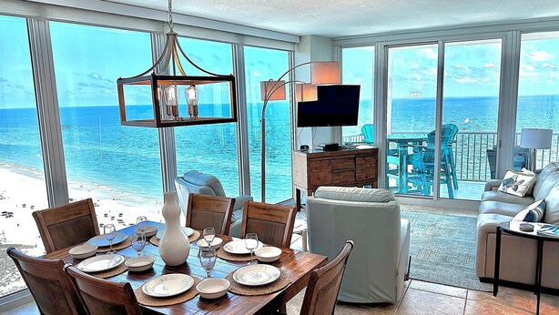A dining area with a view of the ocean, a television, and a balcony with outdoor furniture. - 22nd Floor Beachfront Suite - Amazing Views (Gulf Shores)
