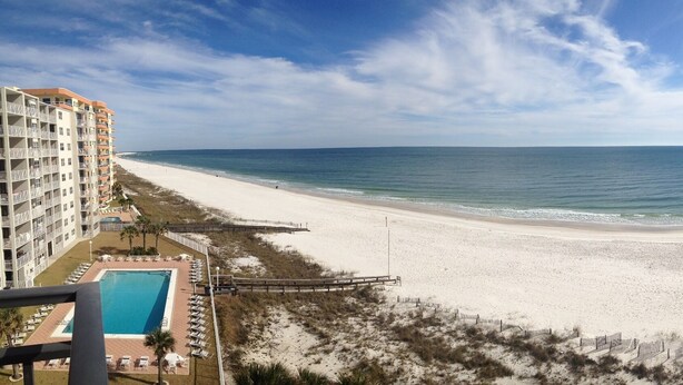 A beach view from a balcony overlooking a sandy beach and ocean.