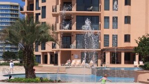 A multi-story building with balconies, a pool, and a water fountain.