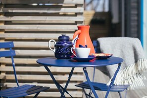 A small round table with a blue ceramic pitcher, a white cup, and a red teapot. - Johanna's Hotel (Bua)