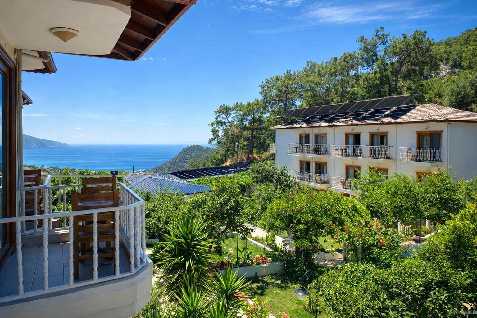 A hotel with a balcony overlooking a scenic view of the sea and greenery.