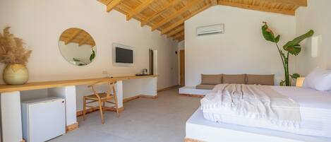 A bedroom with a wooden ceiling, a bed, a desk, a chair, and a television.