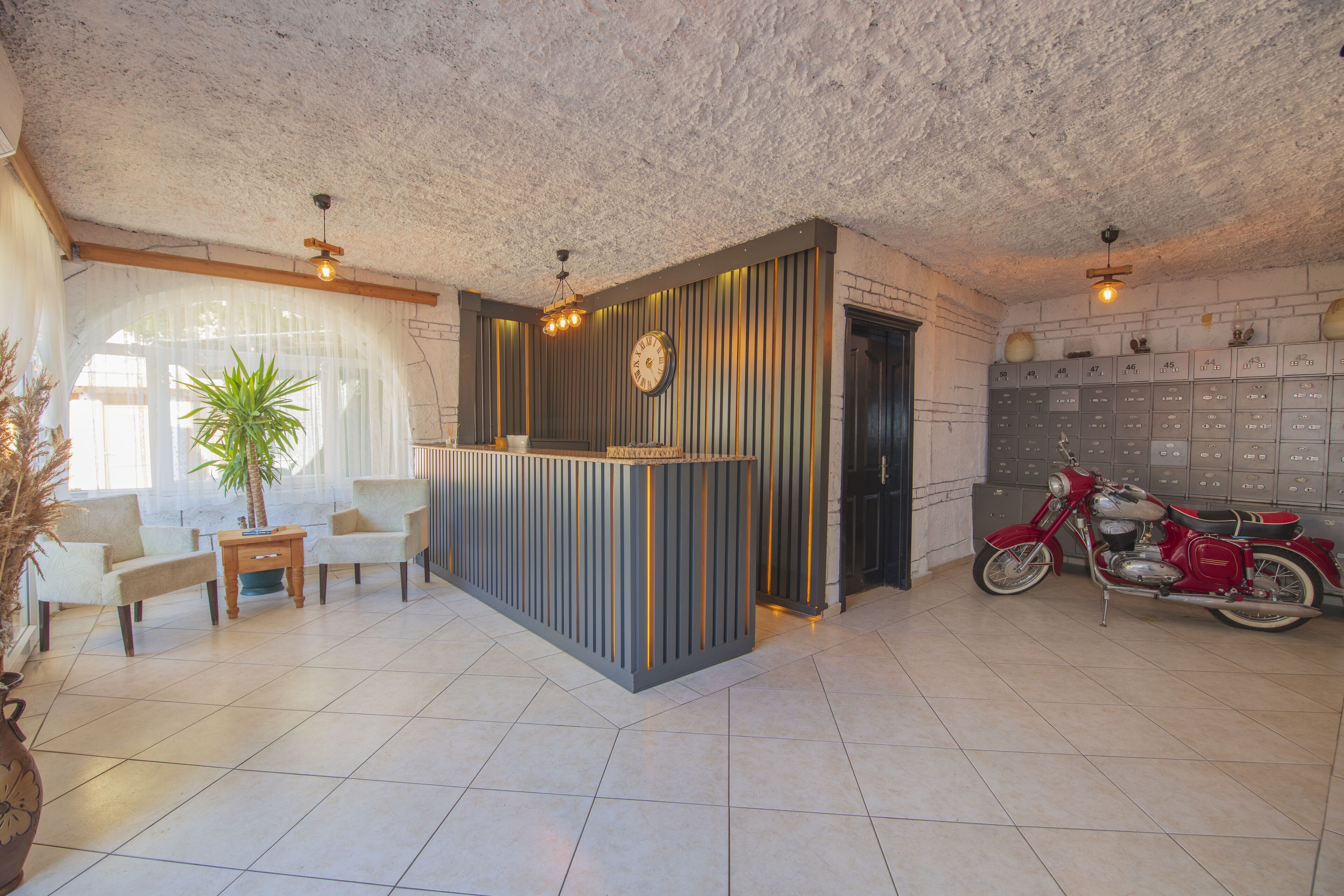 A reception area with a reception desk, seating, a potted plant, a motorcycle, and lockers.