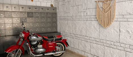 Una motocicleta en una habitación con taquillas y un tapiz de macramé en la pared.