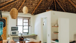 A rustic kitchen with a thatched roof, wooden chairs, a kettle, and a microwave. - Outsite Todos Santos - Work, Connect, Explore (Todos Santos)