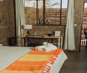 A hotel room with a bed, a desk, a chair, and a view through a window. - Outsite Todos Santos - Work, Connect, Explore (Todos Santos)