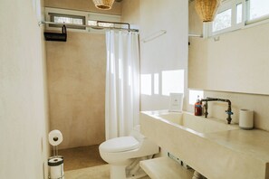 A bathroom with a toilet, sink, and shower curtain. - Outsite Todos Santos - Work, Connect, Explore (Todos Santos)