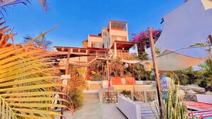 A multi-story building with a modern architectural design, featuring balconies and a staircase leading to the upper levels. - Outsite Todos Santos - Work, Connect, Explore (Todos Santos)