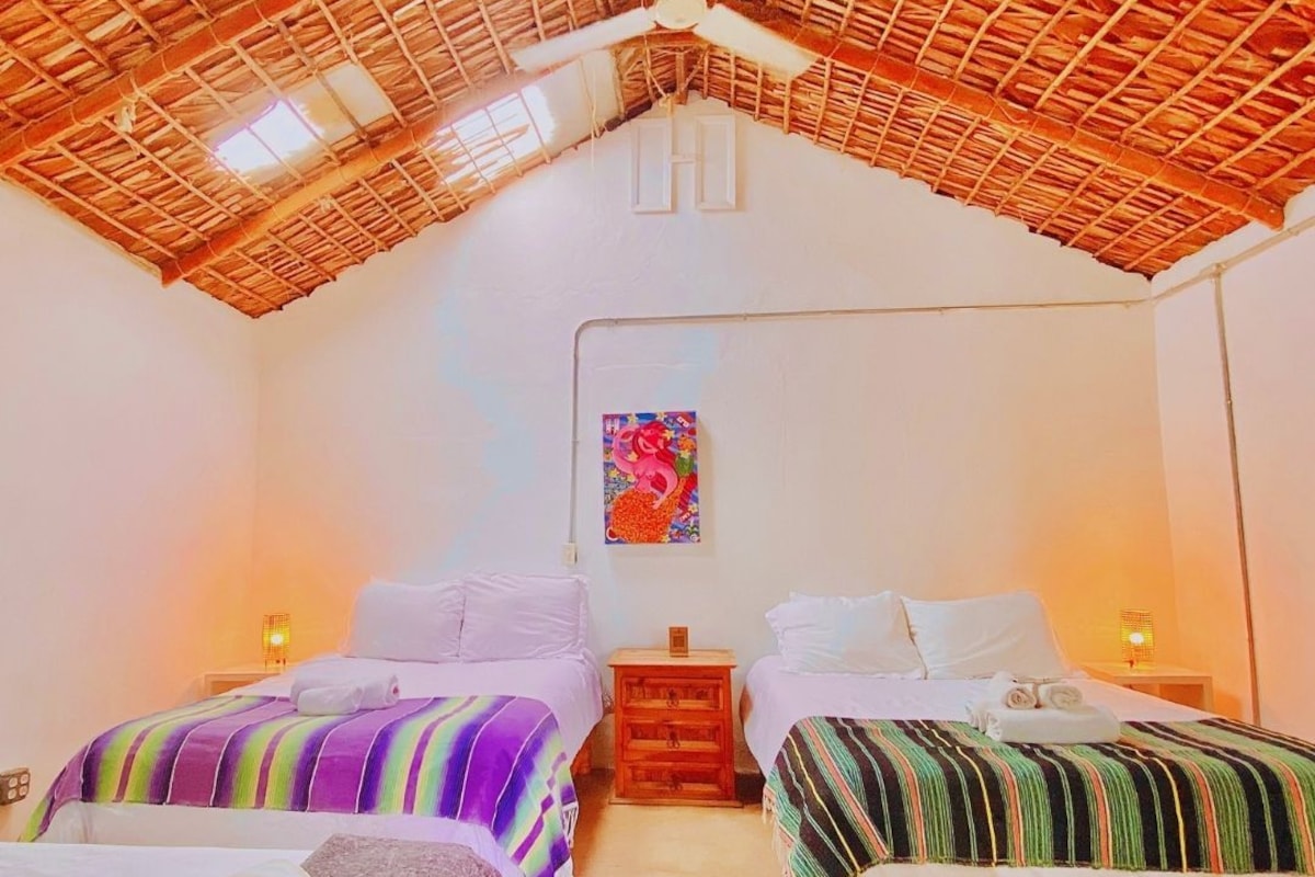 Una habitación con dos camas, un ventilador de techo y un cuadro en la pared.