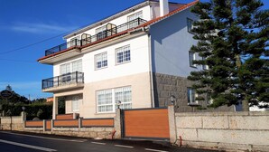Un edificio de dos plantas con balcón, ventanas grandes y una pared de piedra.