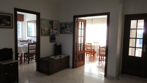 Amplia sala de estar con una mesa de comedor y sillas, un banco y piso de baldosas.