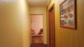 A narrow hallway with wooden walls, a carpeted floor, and a framed picture on the right wall.