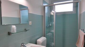 Un baño con lavabo, inodoro y ducha con mampara de vidrio.