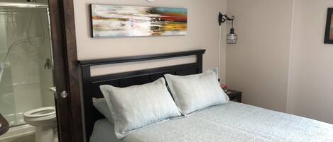 Un dormitorio con una cama, una mesita de noche, una lámpara de pared y un cuadro.