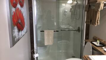 A glass-enclosed shower with a white toilet and a towel rack.