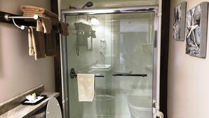 Un baño moderno con cabina de ducha de vidrio, inodoro y lavamanos.