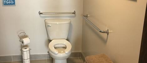 A bathroom with a toilet, a towel rack, and a shelf with towels.
