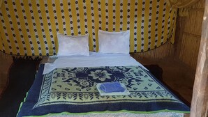 A bed with a patterned bedspread, pillows, and a folded towel.