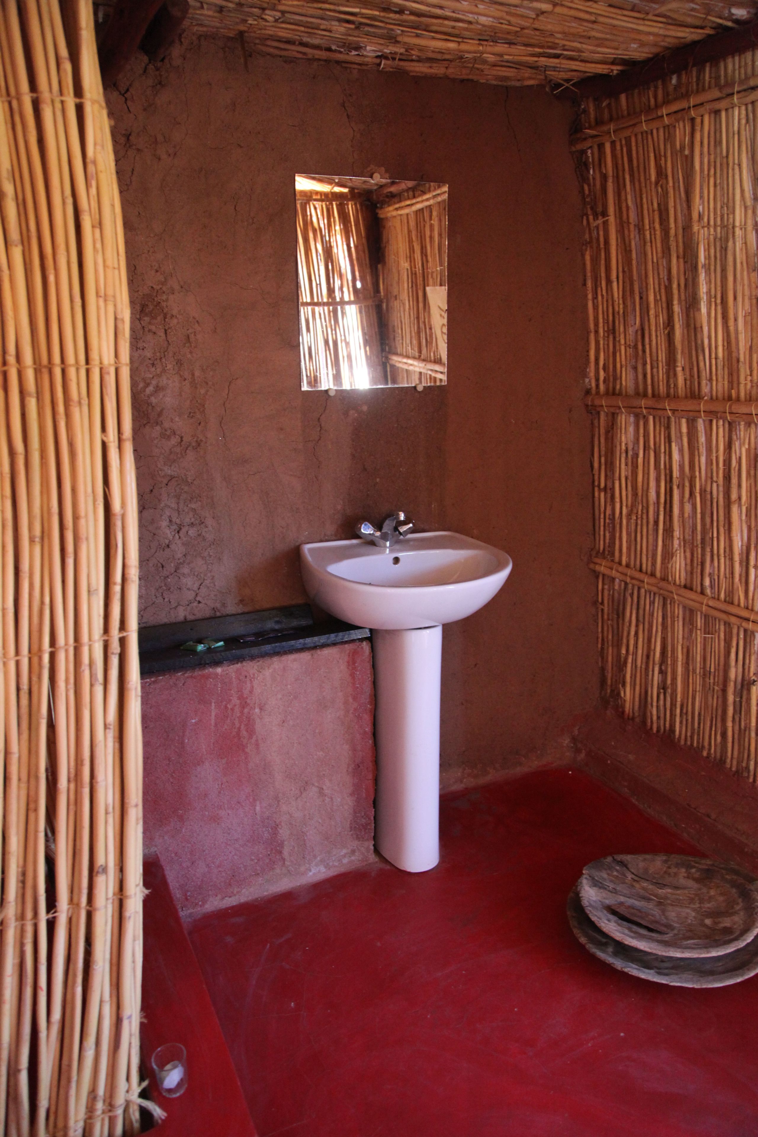 A bathroom with a white sink, a mirror, and a red floor.