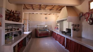 A kitchen with a tiled floor, a wooden ceiling, and a display case.