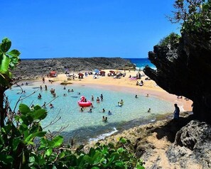 A beach with clear water, people swimming, and a rocky cliff. - Beachfront Paradise With Breathtaking Ocean Views!Private access to Beach. Wifi (Mar Chiquita Manati)