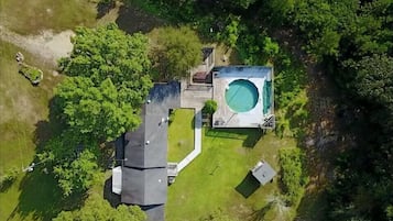 Surrounded by lush greenery, this property features a central pool and a compact main building with easy access.