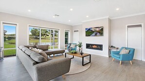 A modern living room with a grey sectional sofa, a blue armchair, and a fireplace. - CHATEAU CALIZA - The Vintage Holiday Houses (POKOLBIN)