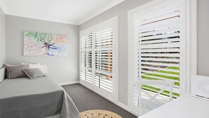 A bedroom with a bed, a painting, and white blinds. - CHATEAU CALIZA - The Vintage Holiday Houses (POKOLBIN)