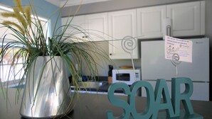 A kitchen with white cabinets, a stainless steel pot with a plant, and a teal sign that reads "SOAR". - Sun, beach, and great savings: huge discounts on holiday destinations! (Cape Coral)