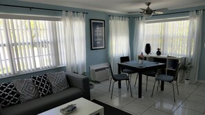 A living room with a sofa, a coffee table, a dining table with chairs, and a ceiling fan. - Sun, beach, and great savings: huge discounts on holiday destinations! (Cape Coral)