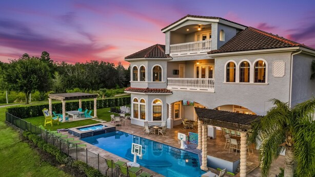 Une maison à deux étages dotée d’une piscine, d’un espace salon extérieur et d’une terrasse couverte.