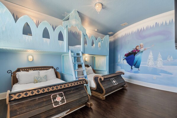 A bedroom with two wooden bunk beds, a ladder, and a mural of a winter scene.