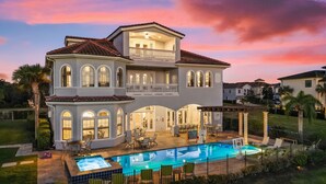 Une maison à deux étages avec une piscine, un espace salon extérieur et un balcon.