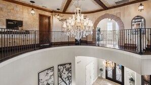 Un intérieur spacieux à plusieurs niveaux, agrémenté d’un magnifique lustre, de murs en pierre et d’une balustrade en bois.