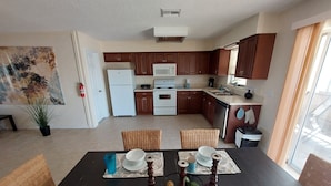 A modern kitchen with wooden cabinets, white appliances, and a dining area with a table set for four.
