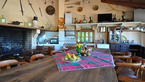 A rustic kitchen with a brick fireplace, wooden furniture, and various kitchen utensils and decorations.