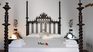 A bedroom with a four-poster bed, a clock on the nightstand, and a decorative wall piece.