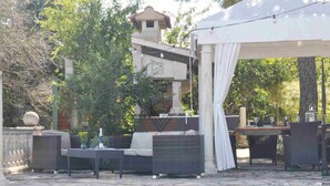 A poolside area with a covered seating area, a small building, and a pergola with string lights.