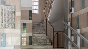 A marble staircase with a metal railing, leading to a landing with a security camera. - World Wide Bed Prenestino (Rome)