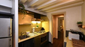 Una cocina moderna con electrodomésticos de acero inoxidable, horno empotrado y un lavamanos. Hay una planta en la encimera y una cesta en la superficie de trabajo.