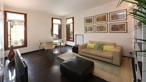 Una sala de estar moderna con un sofá, un reposapiés y un comedor con sillas y una mesa.